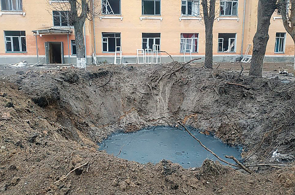 Figure 3: Large bomb crater next to several urban trees. Note the extent of thrown-up soil, damage to many roots, and the contaminated pool at the base of the crater.